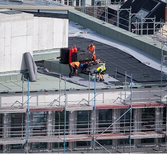 Commercial roofers perform flat roof restoration and repair with scaffolding in Austin.