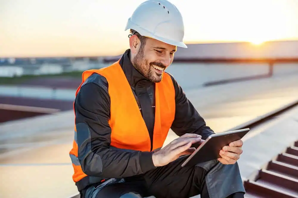 Technician in safety gear on a commercial flat roof inspects for roof repair needs.