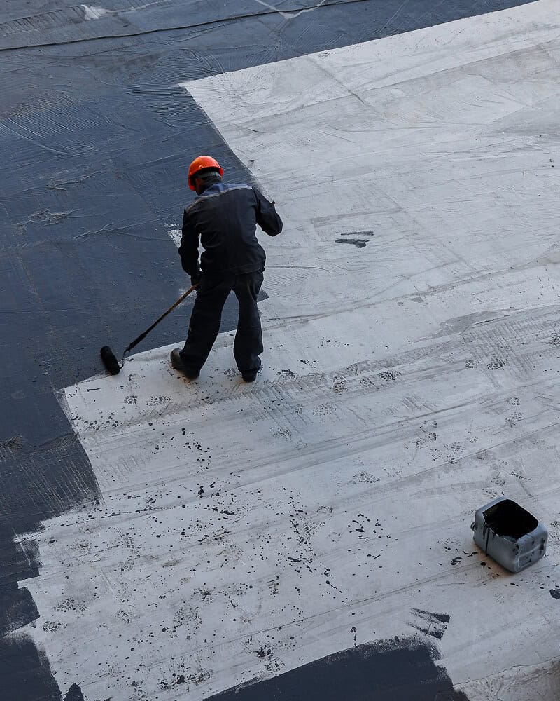 A worker applies coating for commercial flat roof repair and restoration services.