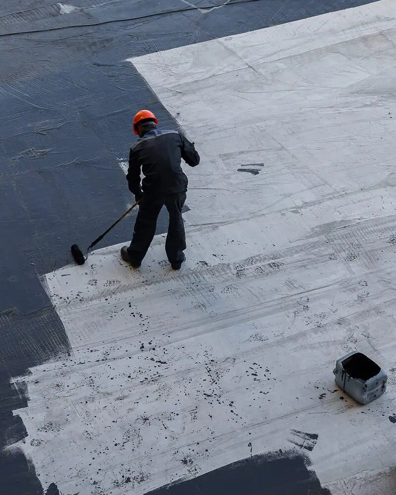 A worker applies coating for commercial flat roof repair and restoration services.