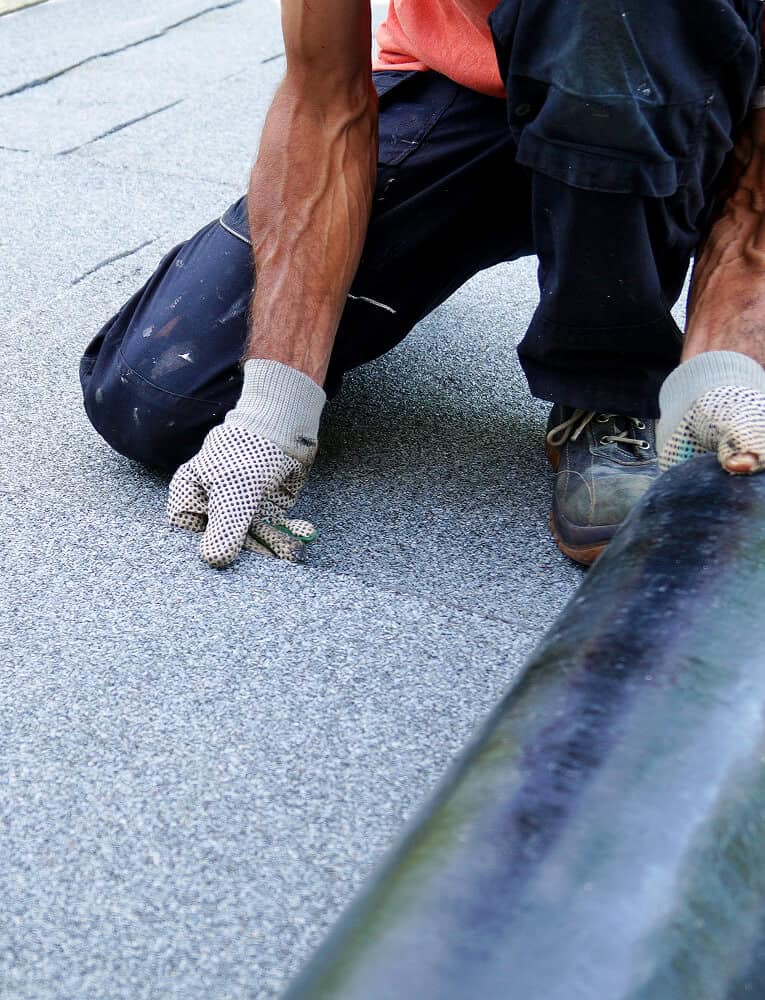 A worker applies roofing material during commercial flat roof restoration and repair.