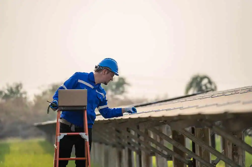 A worker inspects solar panels during commercial flat roof restoration and maintenance.