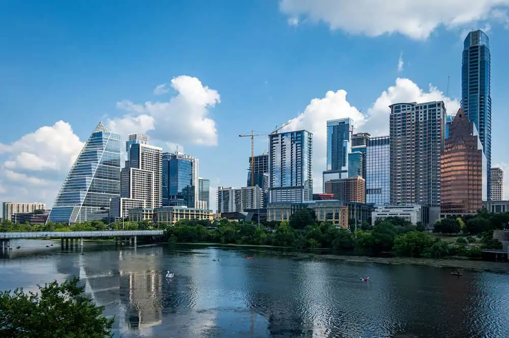City skyline with flat roofs, metal roofing, and commercial roof restoration by river.
