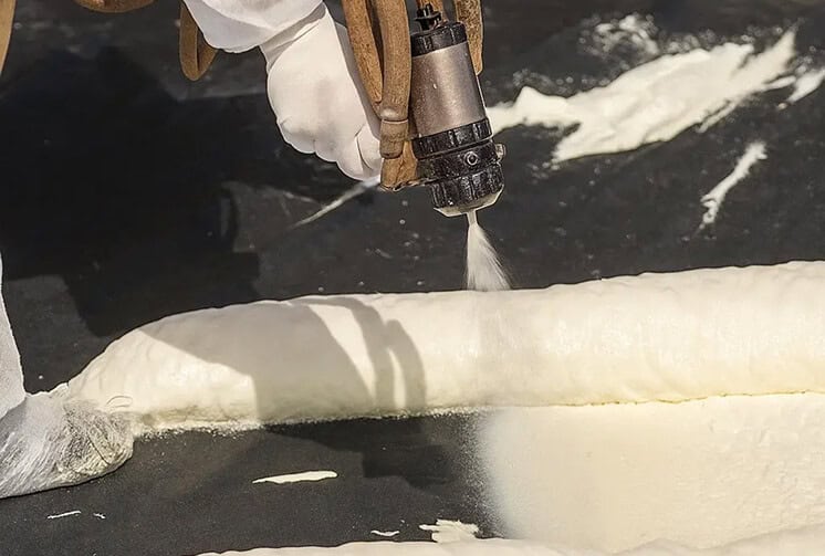 A technician applying spray foam roofing to a commercial building